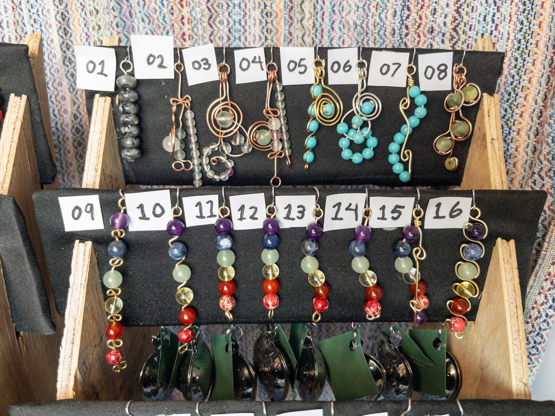 Jewelry display with tea infusers with natural stone charms on a stand with numbered cards.