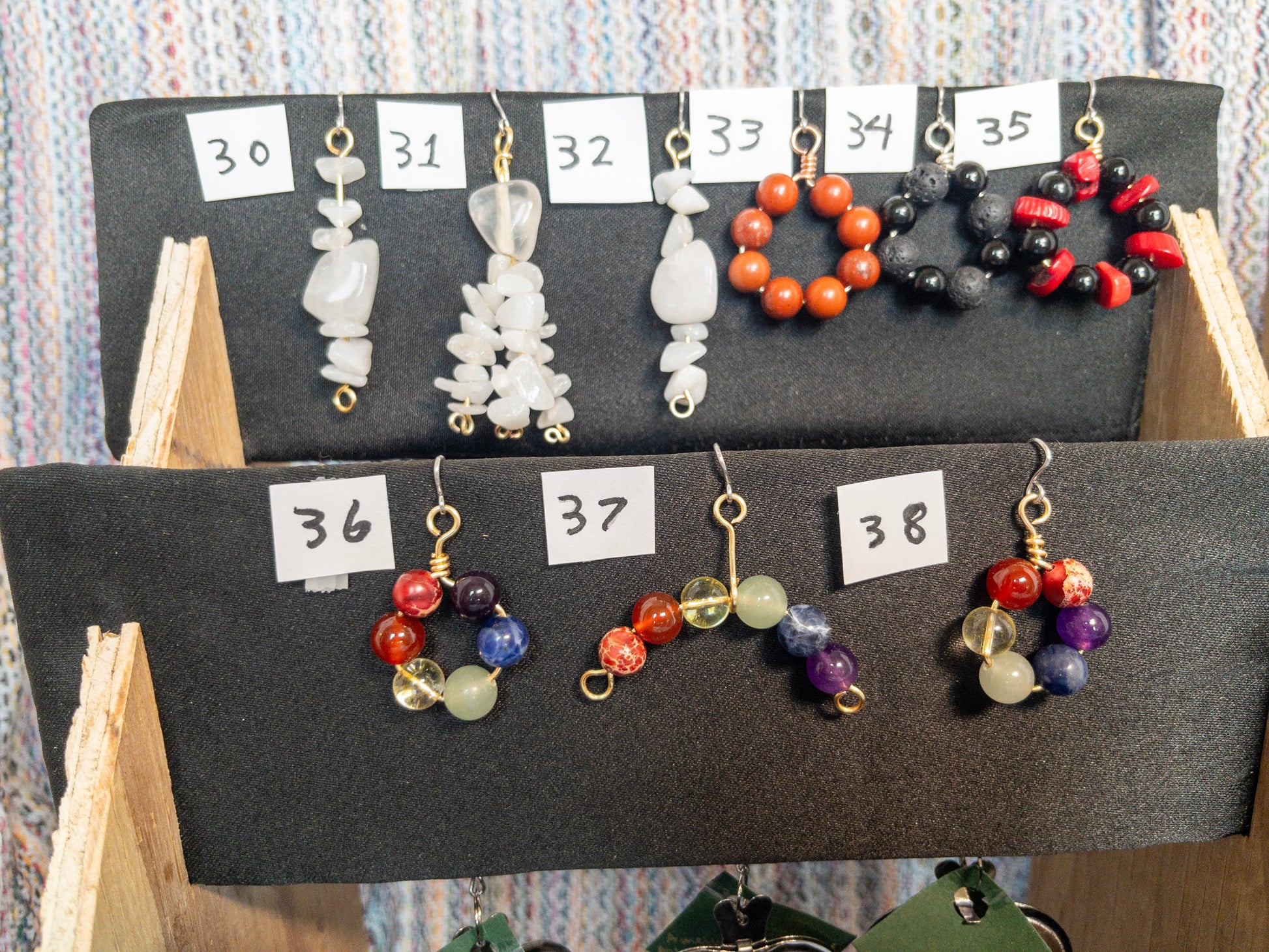 Display of various tea infusers with natural stone charms on a wooden stand